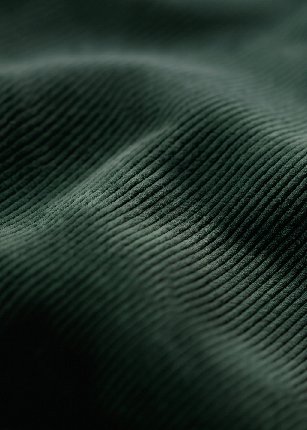 Close-up of dark forest green ribbed fabric texture with a soft peach-pink fabric partially visible along the right edge.