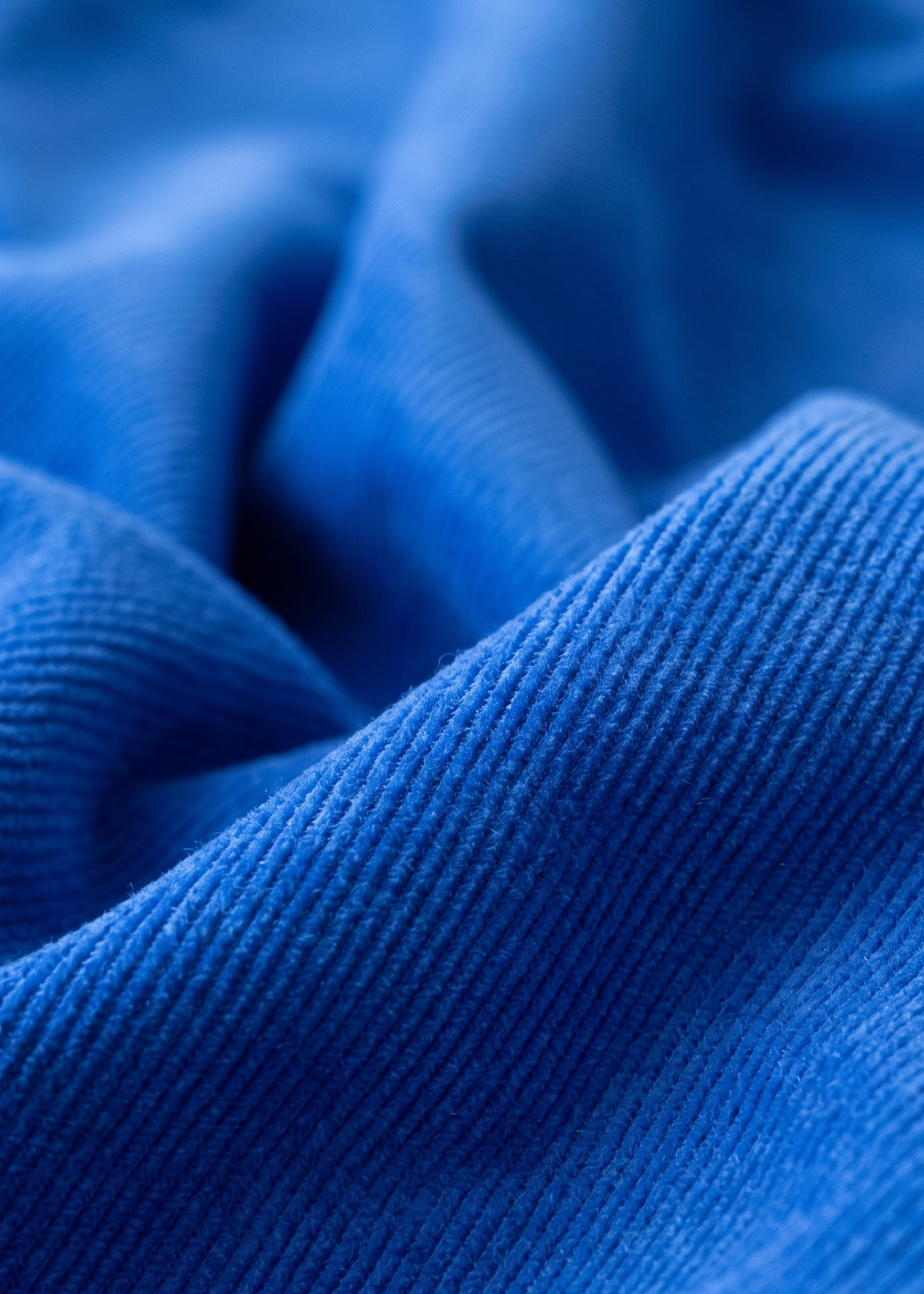 A close-up of textured blue fabric with soft folds and a fine ribbed weave.